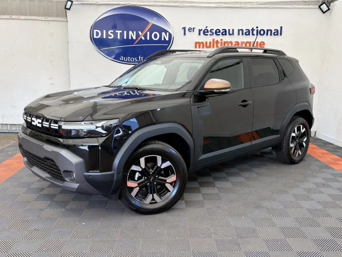 Dacia Duster 2025 noir en 3/4 avant droit, avec jantes bicolores et rétroviseurs couleur cuivre.