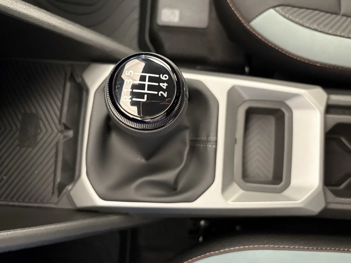 Le levier de vitesses manuel noir du Dacia Duster 2025, vue plongeante sur la console centrale et les sièges partiellement visibles.