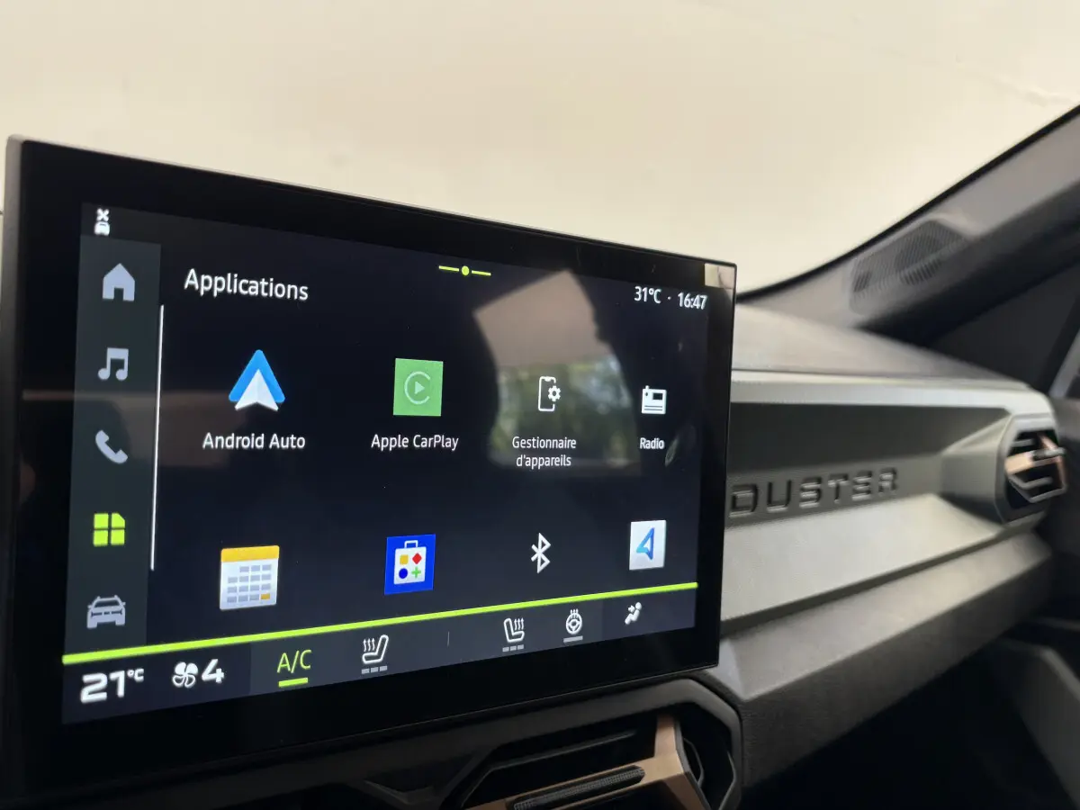 Écran tactile central affichant Apple CarPlay dans l'habitacle du Dacia Duster noir, version 2025.