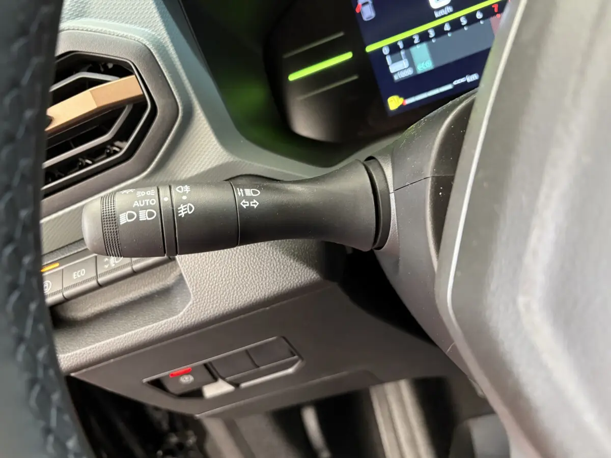 Gros plan sur la manette de clignotants et commandes lumineuses du tableau de bord du Dacia Duster noir 2025.
