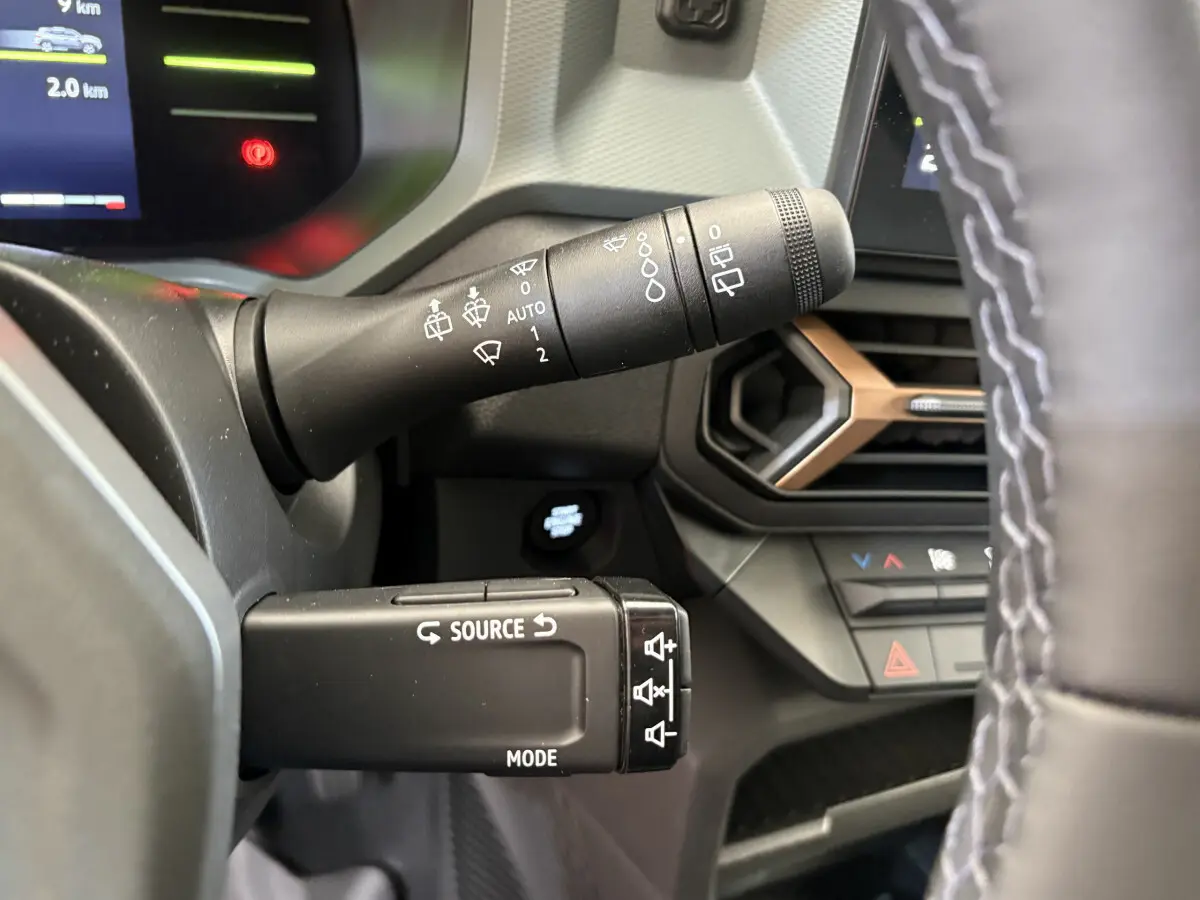 Gros plan sur les commandes au volant du Dacia Duster noir 2025, montrant les leviers de clignotants et multimédia.
