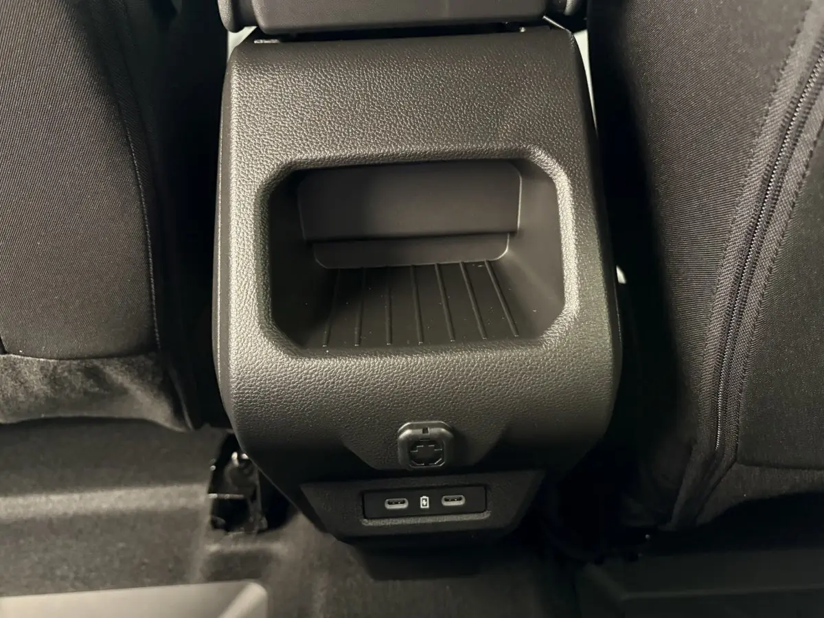 Prise USB arrière et rangement noir entre les sièges arrière du Dacia Duster 2025 hybride essence.