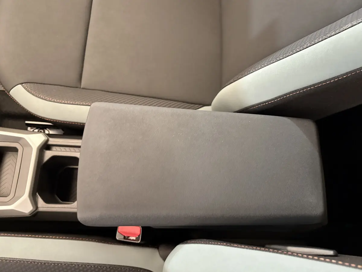 Gros plan sur l'accoudoir central noir et les sièges bicolores gris et noir du Dacia Duster 2025 hybride.