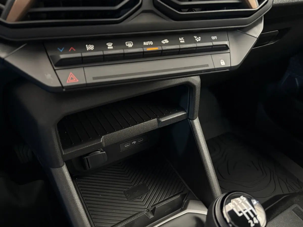 Gros plan sur la console centrale du Dacia Duster noir 2025, avec commandes climatisation et boîte manuelle visible