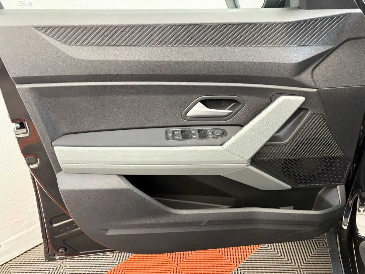 Vue rapprochée de la porte avant gauche noire du Dacia Duster 2025 avec commandes électriques et insert gris clair.