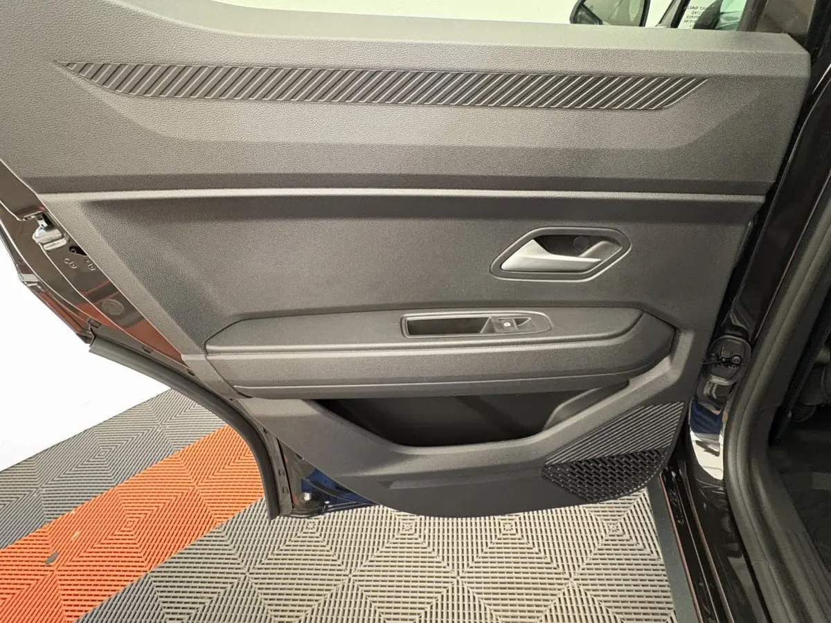 Gros plan sur la porte arrière droite noire du Dacia Duster 2025, montrant la poignée et les commandes de vitre.