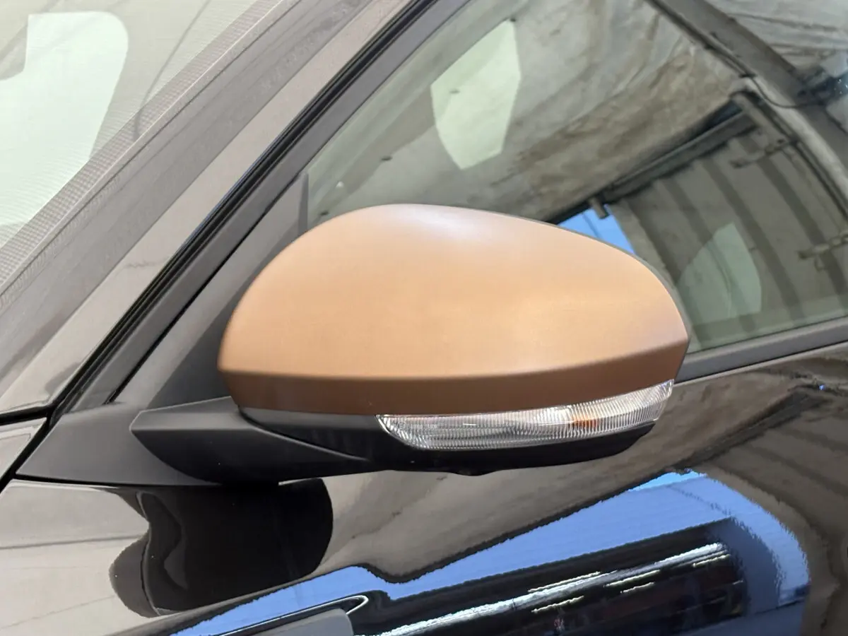 Gros plan sur le rétroviseur côté gauche du Dacia Duster 2025 noir avec clignotant intégré et coque marron.