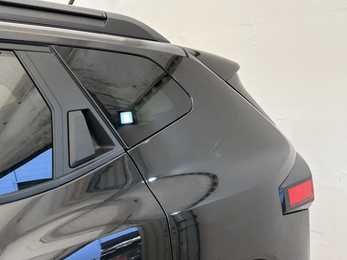 Dacia Duster noir vu de l'arrière côté gauche, mettant en valeur la lunette arrière et le feu arrière rectangulaire.