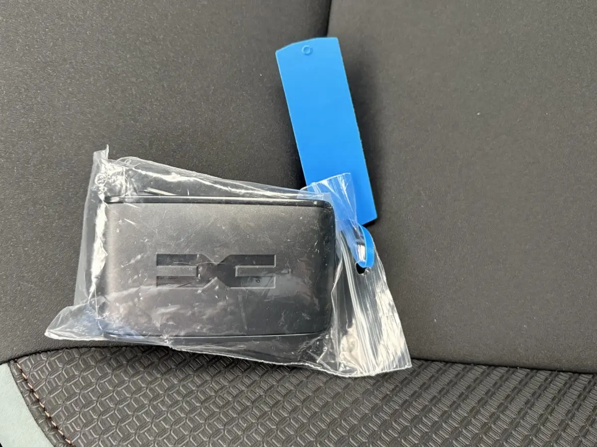 Clé noire Dacia Extreme Mild Hybrid posée sur un siège tissu noir avec surpiqûres marron, vue rapprochée intérieure.