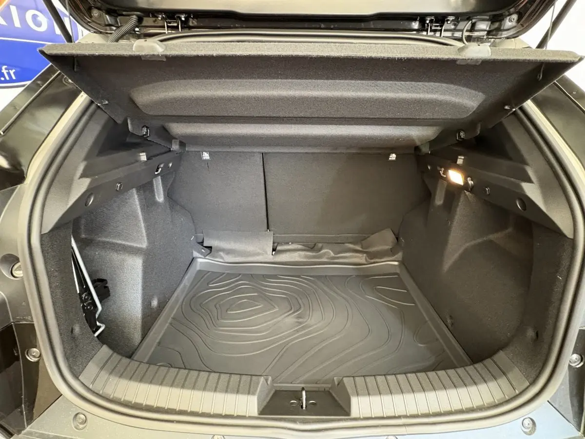 Coffre ouvert noir du Dacia Duster 2025, vue intérieure montrant l'espace de chargement et la moquette protectrice.