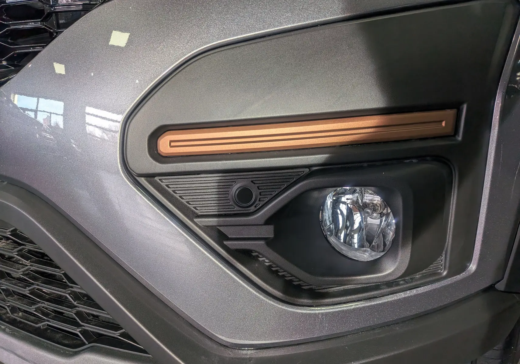Gros plan sur le feu antibrouillard droit de la Dacia Sandero Stepway gris schiste avec insert décoratif cuivre.