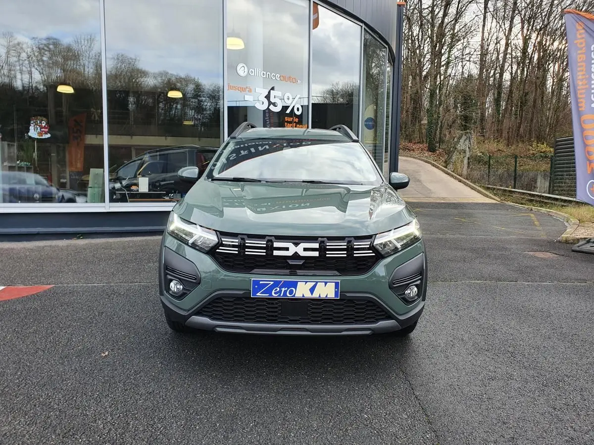 Vue frontale d'un Dacia Jogger 2024 hybride en vert lichen avec barres de toit et calandre noire.