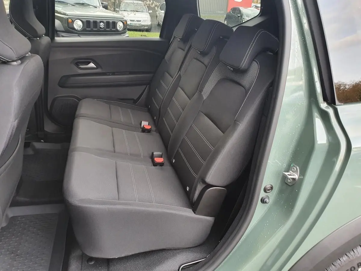 Vue latérale des sièges arrière noirs du Dacia Jogger 2024 en Licken Kaki avec porte arrière ouverte.