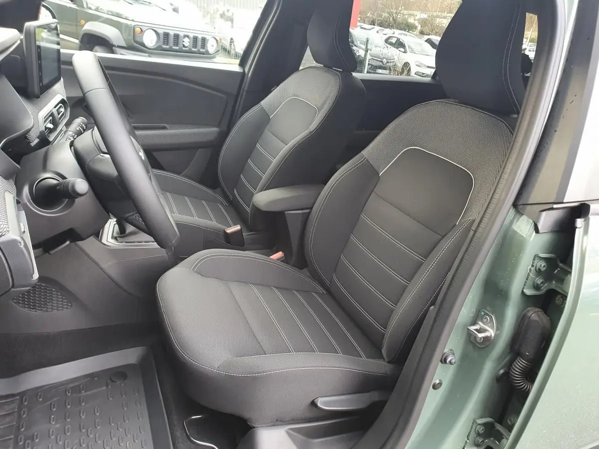 Vue intérieure côté conducteur du Dacia Jogger 2024 en Licken Kaki, montrant les sièges avant noirs avec accoudoir.
