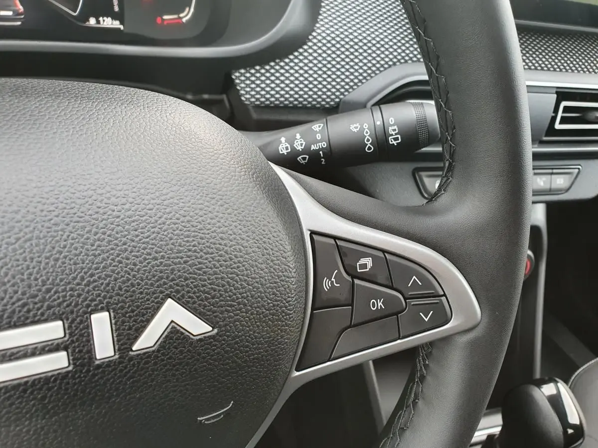 Gros plan sur le volant cuir noir du Dacia Jogger 2024 avec commandes multifonctions et tableau de bord partiel.