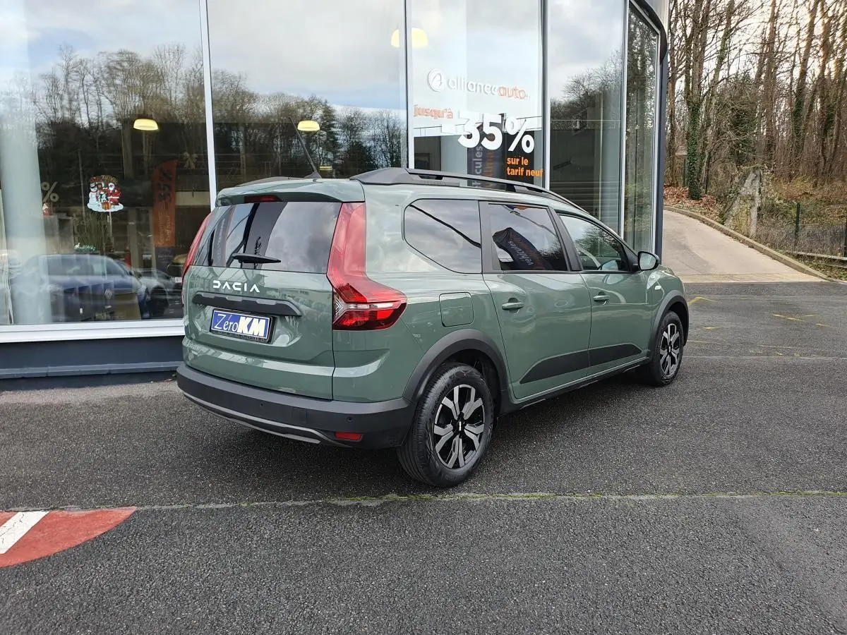 Vue 3/4 arrière droite du Dacia Jogger 2024 hybride en Licken Kaki avec barres de toit et feux arrière LED distinctifs.