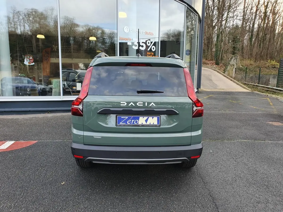 Vue arrière d'un Dacia Jogger 2024 vert Licken Kaki avec feux verticaux et barres de toit visibles.