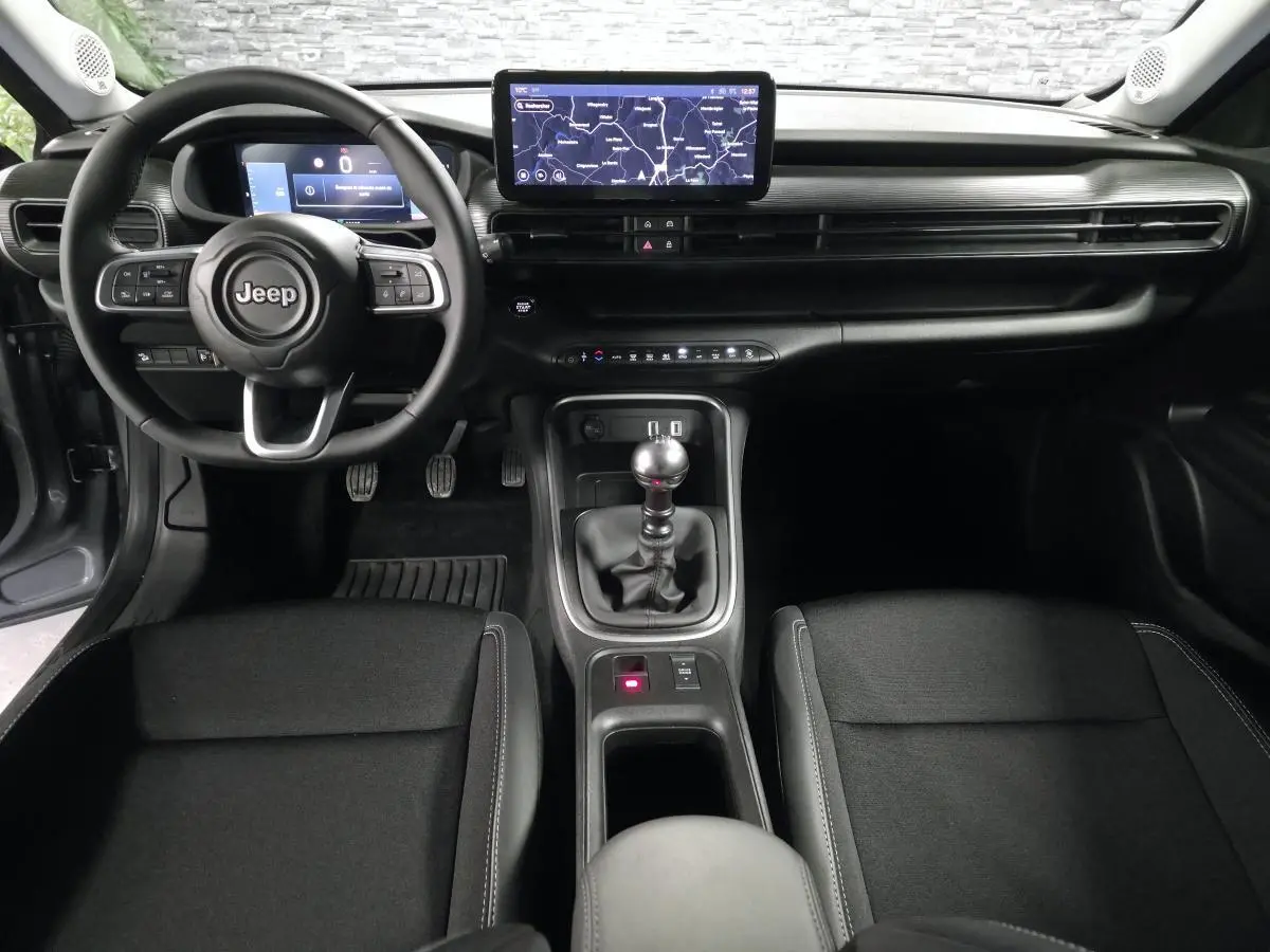 Vue intérieure avant du Jeep Avenger 2025, montrant le volant, la boîte manuelle et l'écran tactile central.