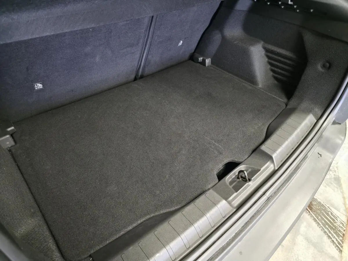 Vue rapprochée du coffre gris du Jeep Avenger 2025, montrant le plancher modulable et la bordure en plastique.