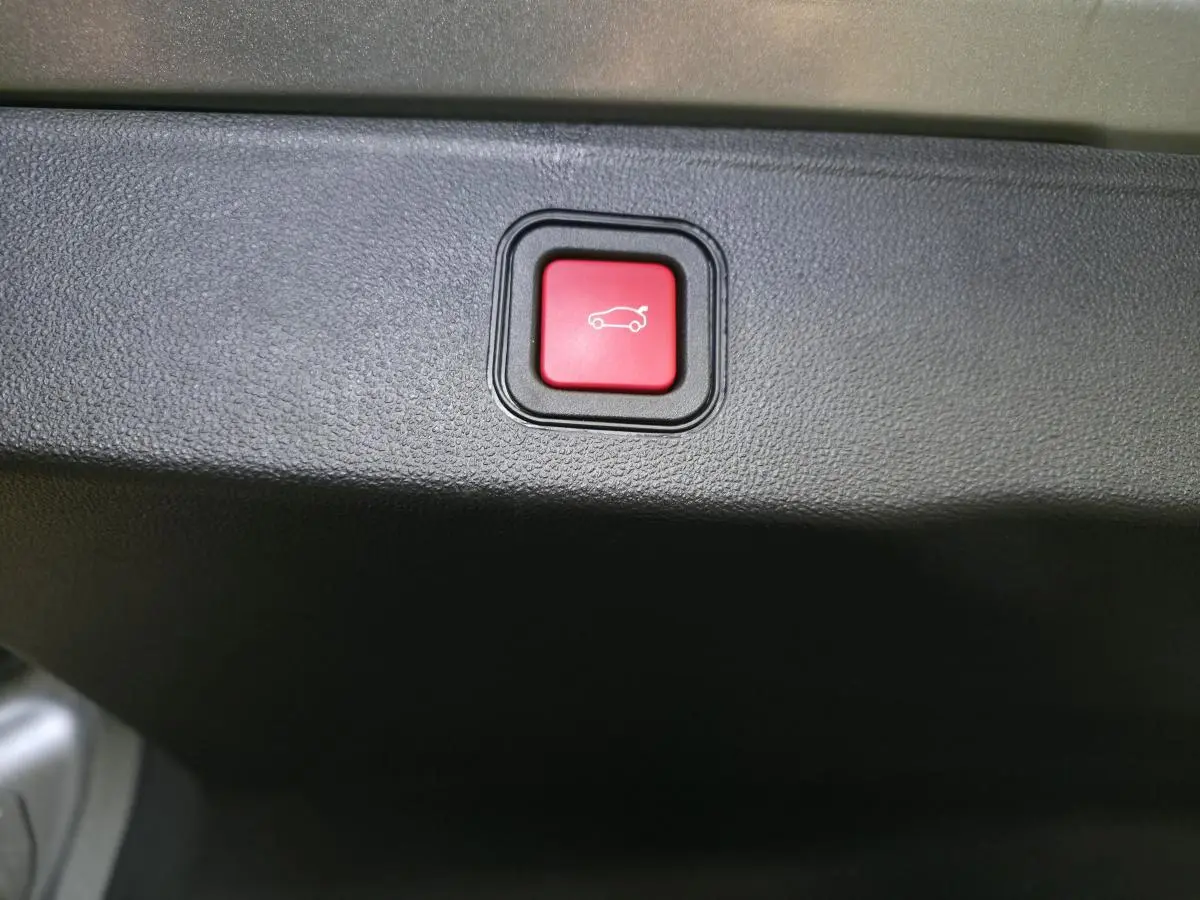 Bouton rouge d'ouverture électrique du hayon sur la garniture intérieure du coffre du Jeep Avenger gris 2025.