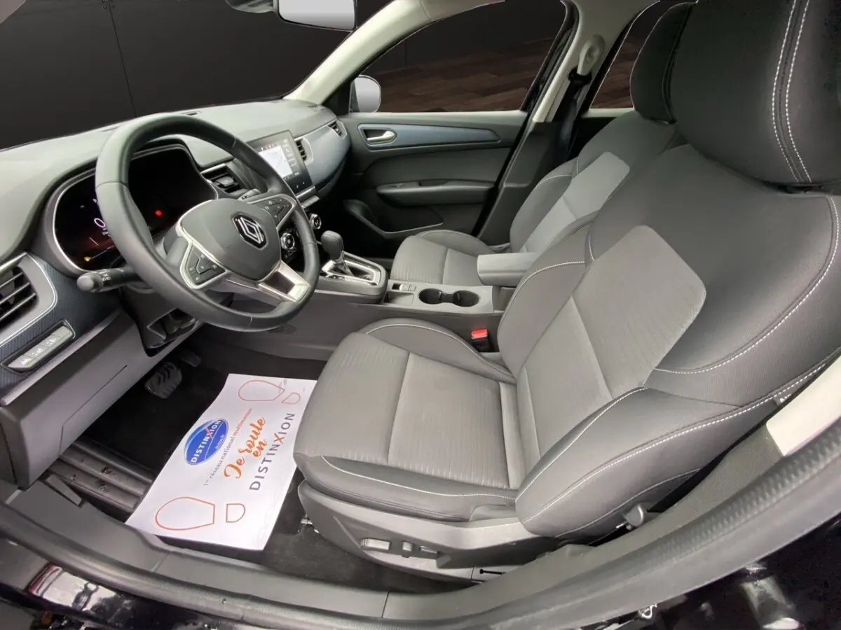 Vue intérieure côté conducteur de la Renault Arkana 2024, sièges gris et volant multifonctions noir avec logo Renault.