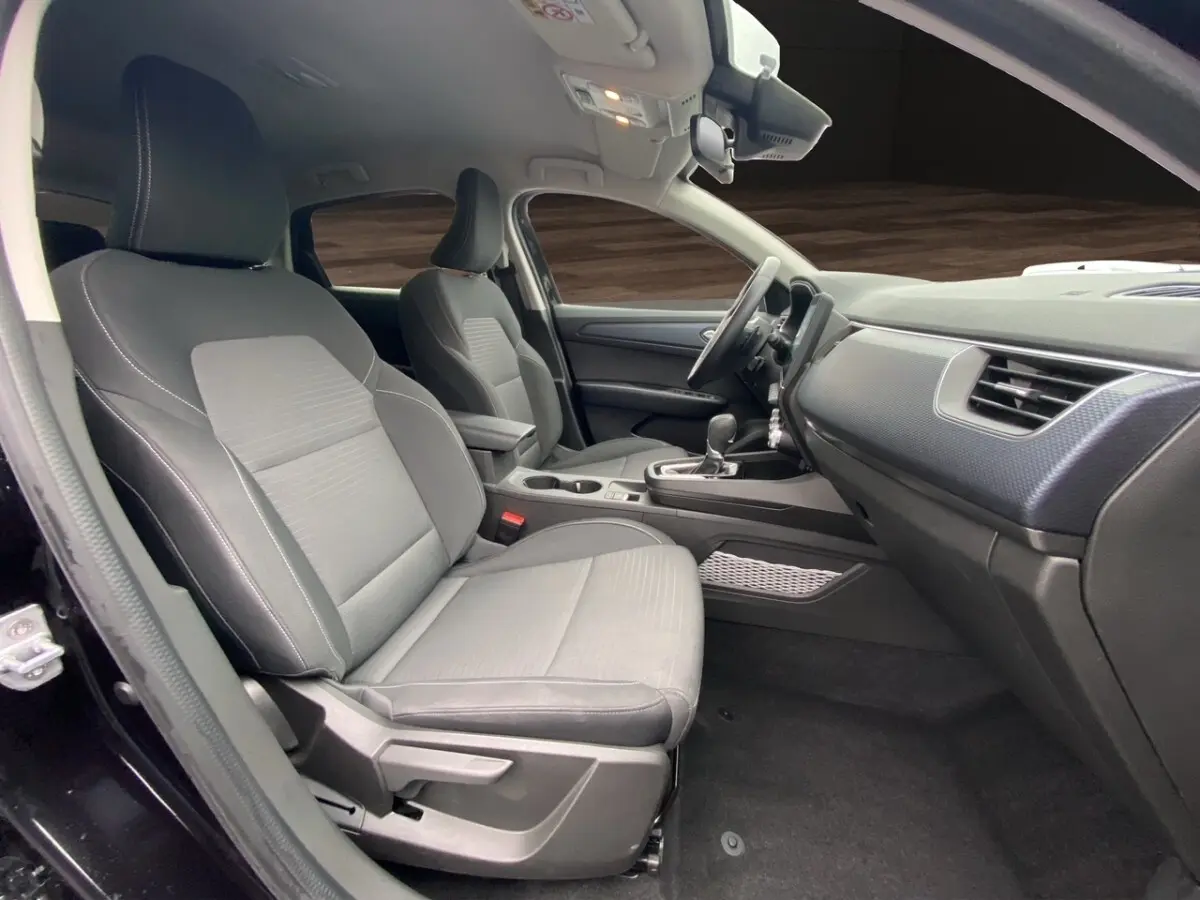 Vue intérieure côté conducteur du Renault Arkana noir 2024, sièges tissu gris avec console centrale et tableau de bord moderne.