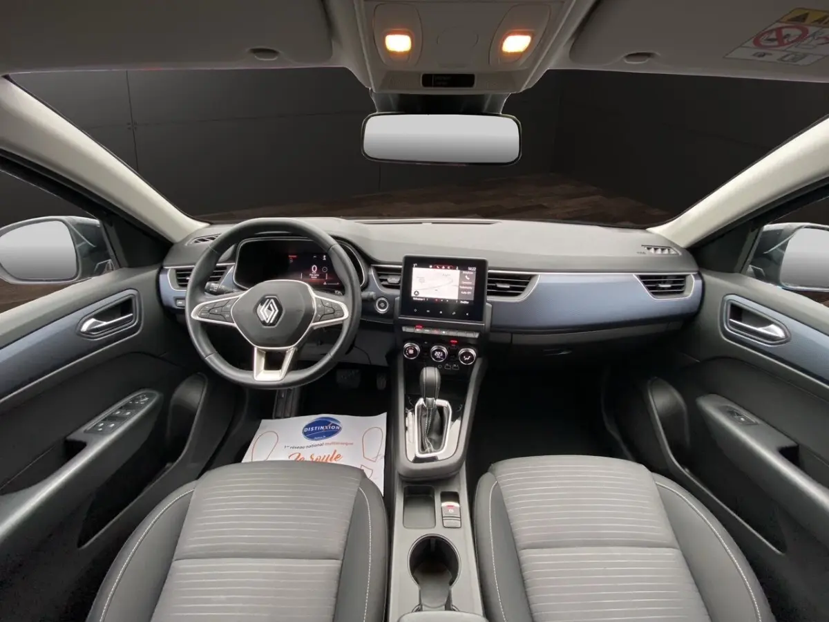 Vue intérieure avant du Renault Arkana 2024 noir, tableau de bord moderne avec écran tactile central et volant multifonctions.