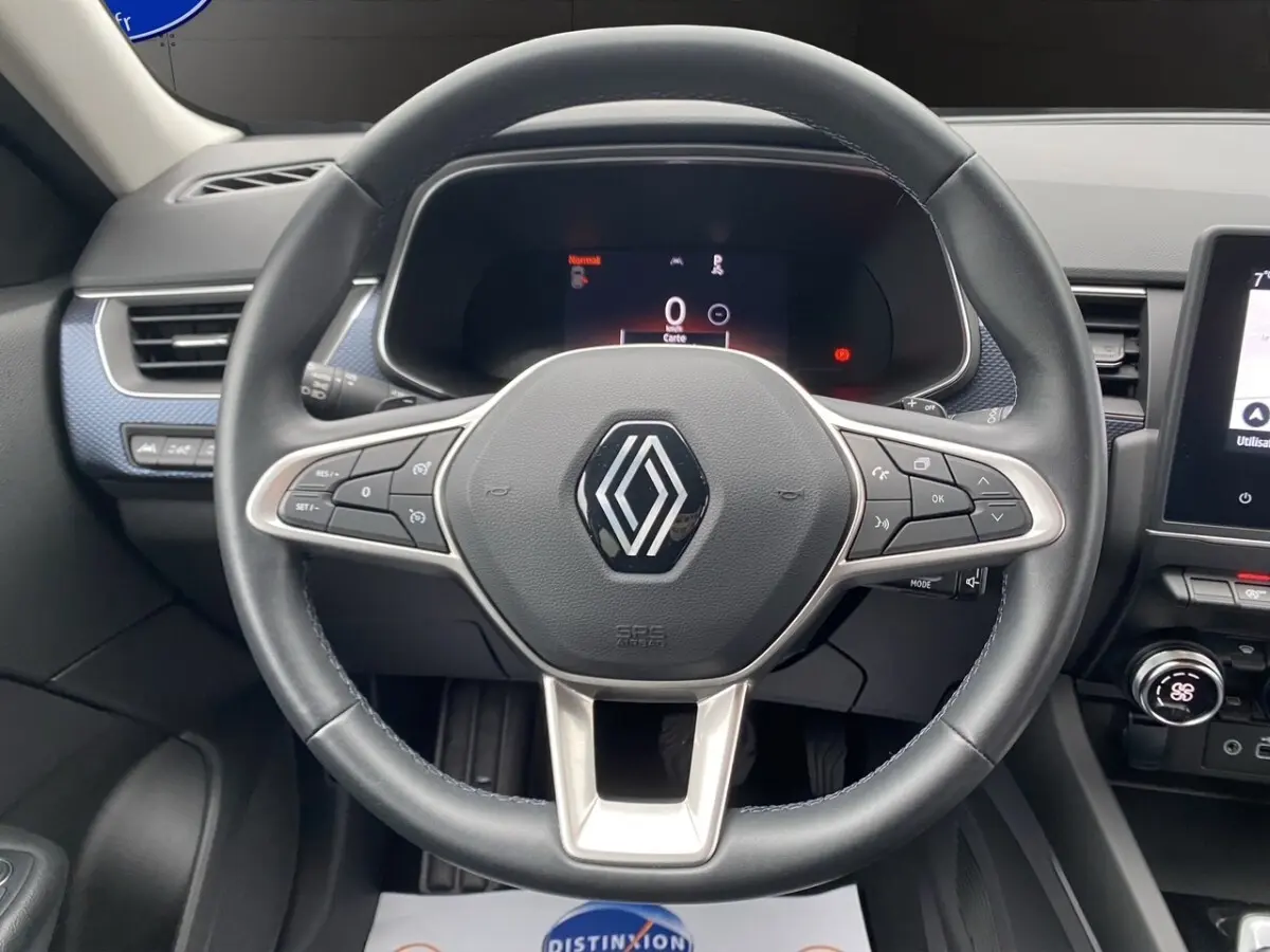 Vue rapprochée du volant cuir noir et alu du Renault Arkana 2024 avec tableau de bord numérique et écran tactile central.
