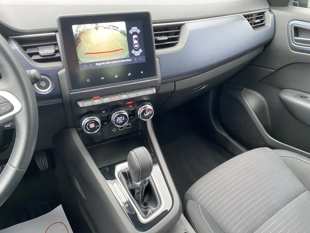 Vue intérieure côté passager du tableau de bord et console centrale noire du Renault Arkana 2024 avec écran tactile et levier de boîte auto.