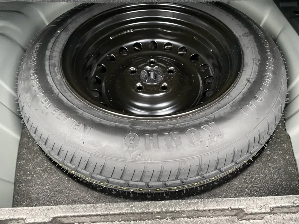 Gros plan sur la roue de secours noire en acier dans le coffre du Renault Arkana 2024 noir.