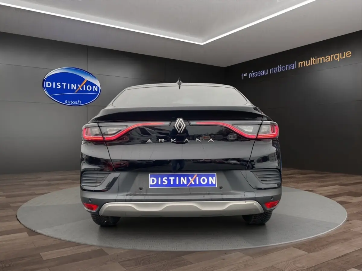 Vue arrière d'un Renault Arkana noir 2024 avec feux LED reliés et logo central sur fond showroom.
