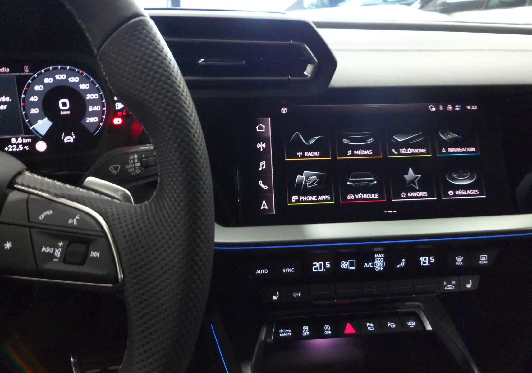 Intérieur de l'Audi A3 Sportback 2025 en noir, vue du tableau de bord avec écran tactile et volant perforé.