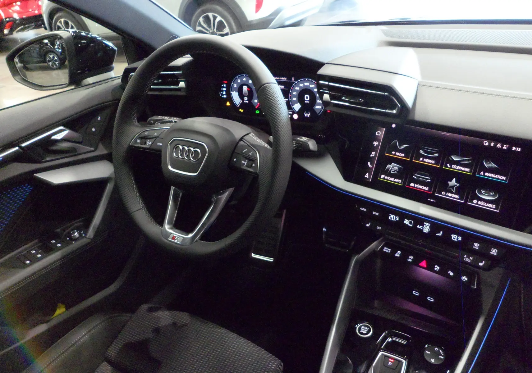 Vue intérieure côté conducteur de l'Audi A3 Sportback 2025 avec tableau de bord numérique et ambiance lumineuse bleue