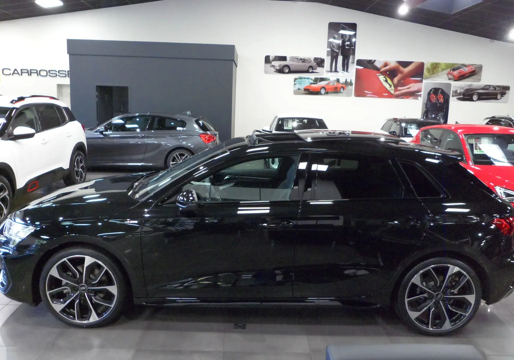 Profil latéral droit d'une Audi A3 Sportback 35 TFSI S-Line en noir Mythe, avec jantes alliage bicolores et toit ouvrant.