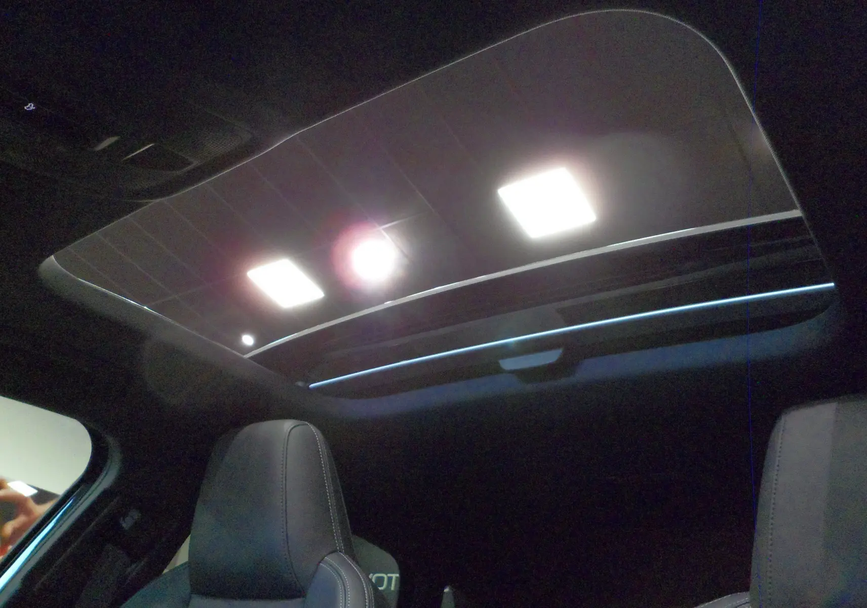 Toit panoramique ouvert vu de l'intérieur sur une Audi A3 Sportback 35 TFSI S-Line noir Mythe, sièges avant en cuir noir.