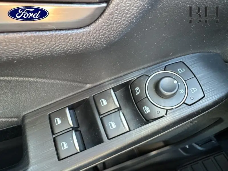 Commande des vitres et réglage des rétroviseurs côté conducteur dans l'habitacle du Ford Kuga gris Solar 2023.