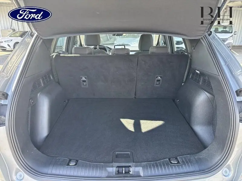 Coffre ouvert du Ford Kuga gris Solar Métallisé 2023, montrant l'espace de chargement et la banquette arrière en position verticale.