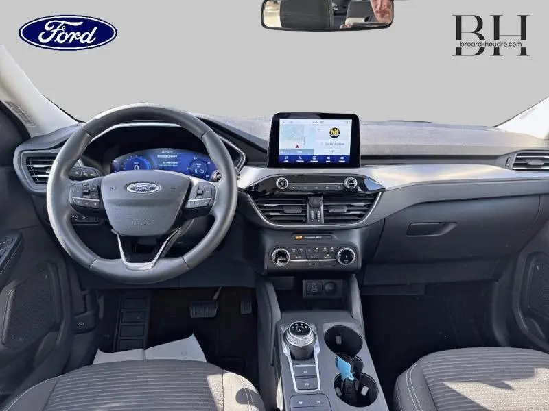 Vue intérieure avant du Ford Kuga 2023 avec tableau de bord moderne, écran tactile et volant cuir multifonction.
