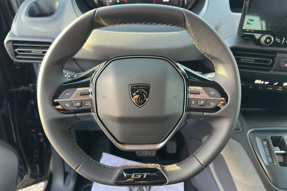 Vue rapprochée du volant cuir multifonctions noir avec logo Peugeot et badge GT du Rifter 2025.