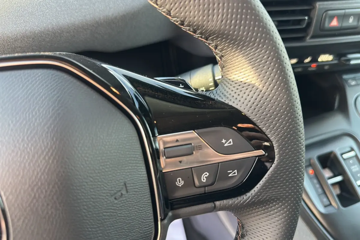 Gros plan sur les commandes multifonctions du volant cuir perforé du Peugeot Rifter noir perla nera, version 2025.