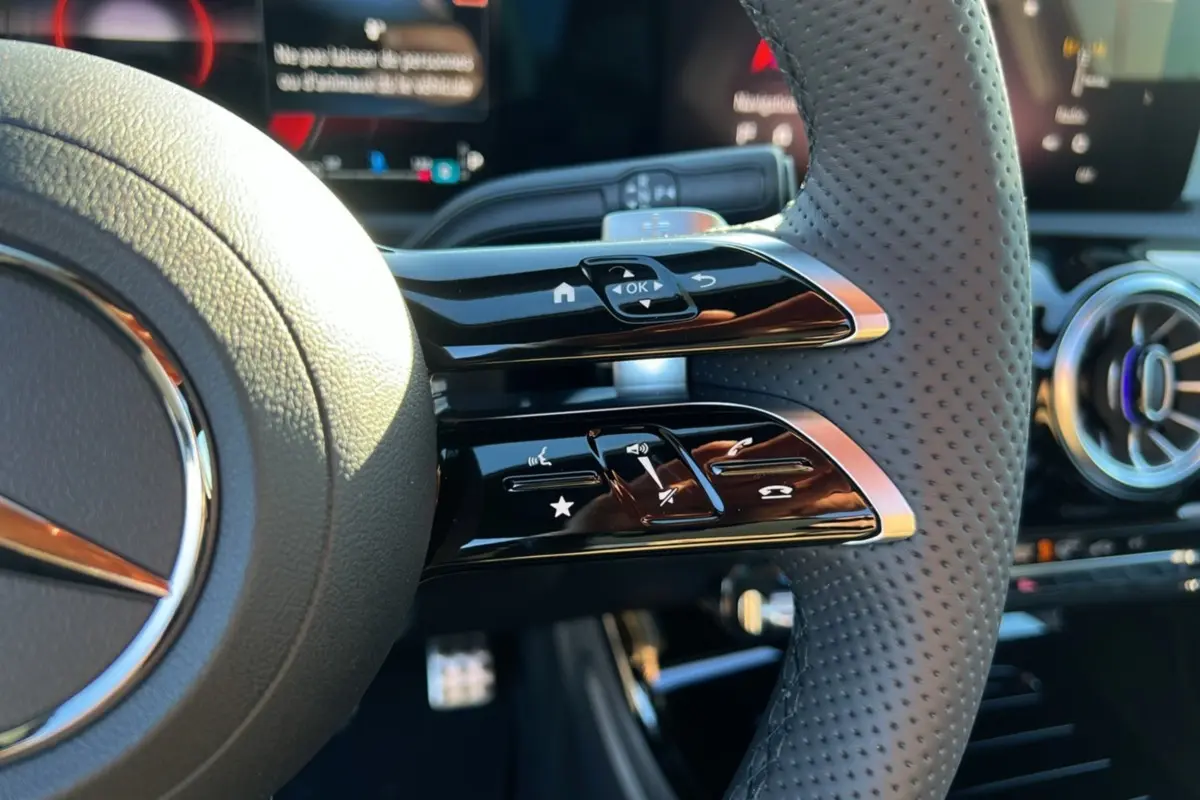 Gros plan sur le volant cuir perforé de la Mercedes Classe A 200D BVA Exclusive Design avec commandes multifonctions.