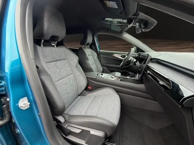 Vue intérieure côté conducteur du Renault Austral bleu, mettant en valeur les sièges tissu gris et le tableau de bord moderne.