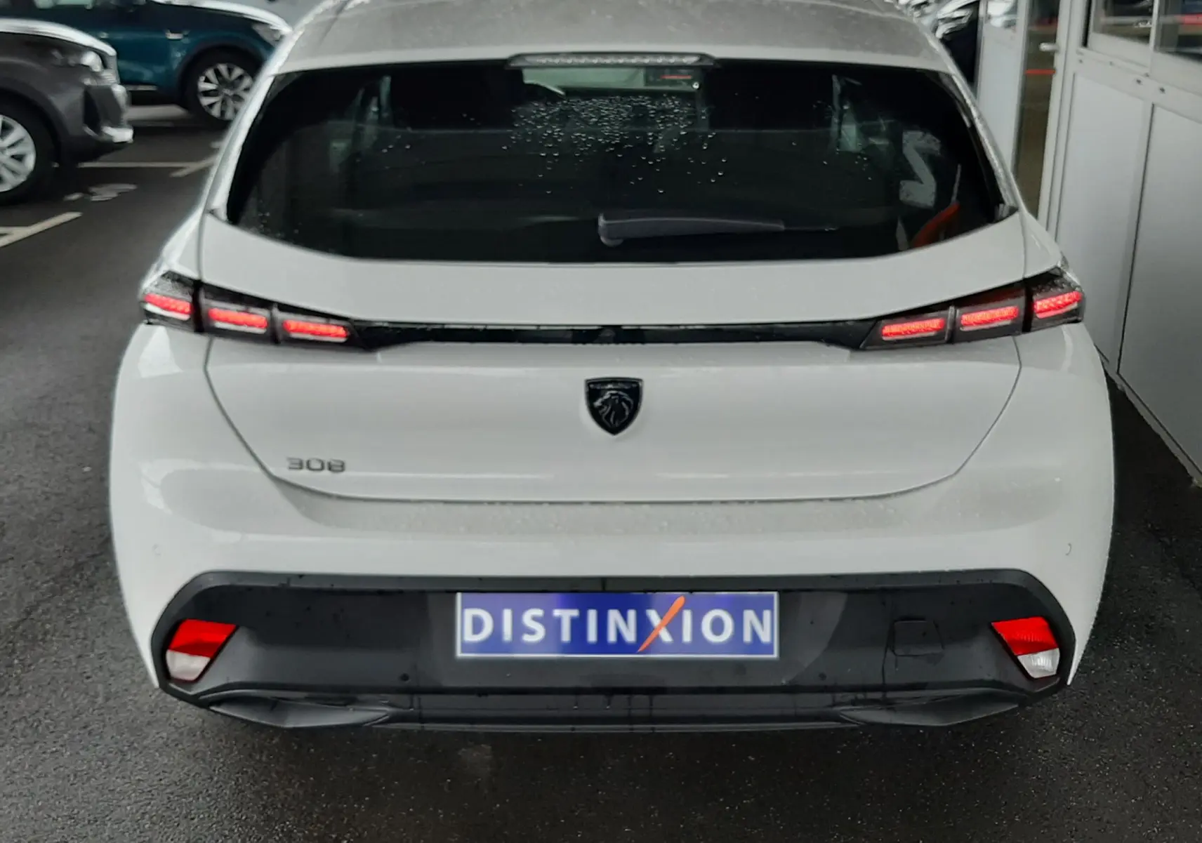 Vue arrière d'une Peugeot 308 blanche banquise 2022 avec feux LED et logo lion noir sur le hayon.