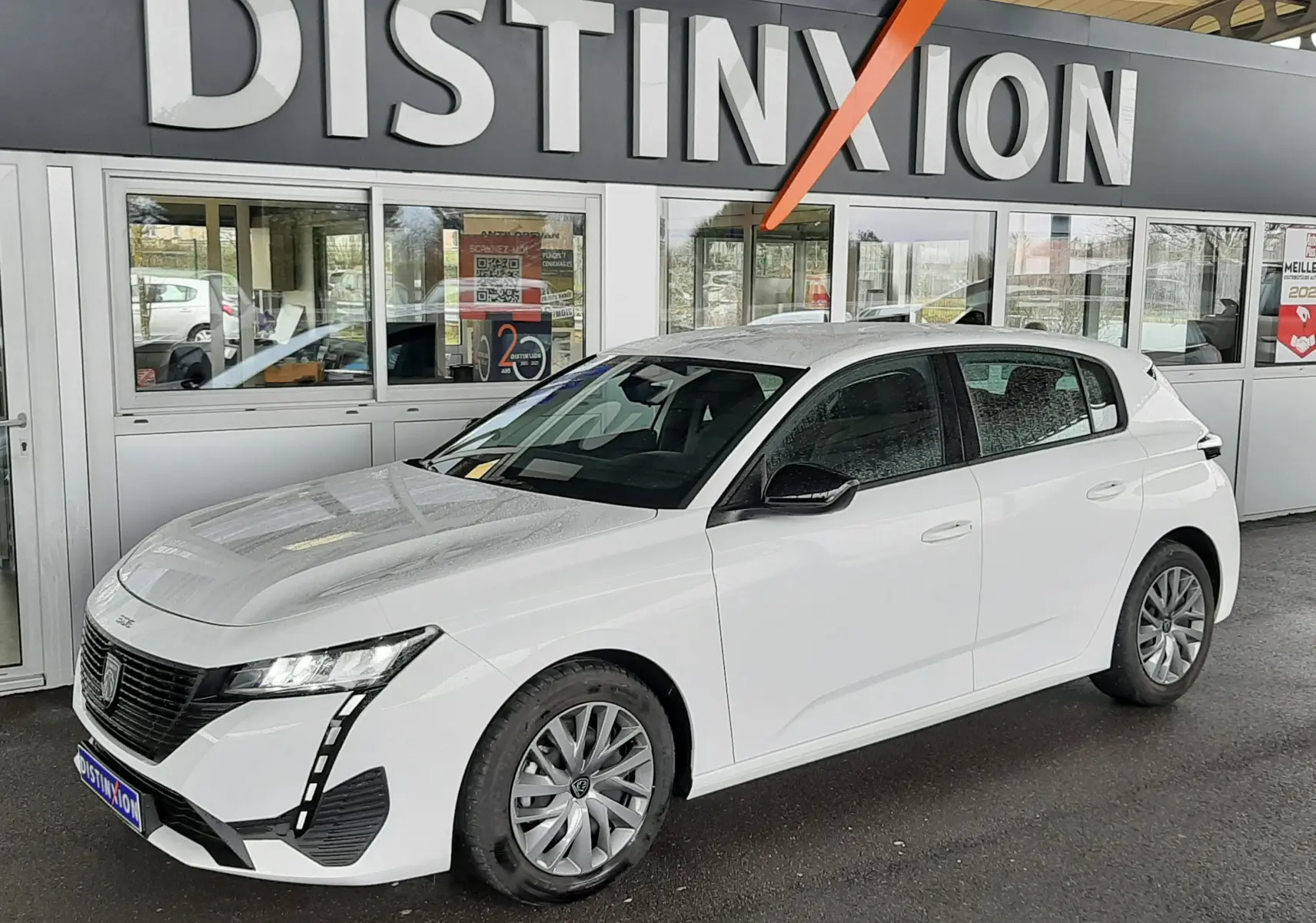 Peugeot 308 blanc banquise vue 3/4 avant droit sous abri, mettant en valeur ses phares LED et sa calandre noire.