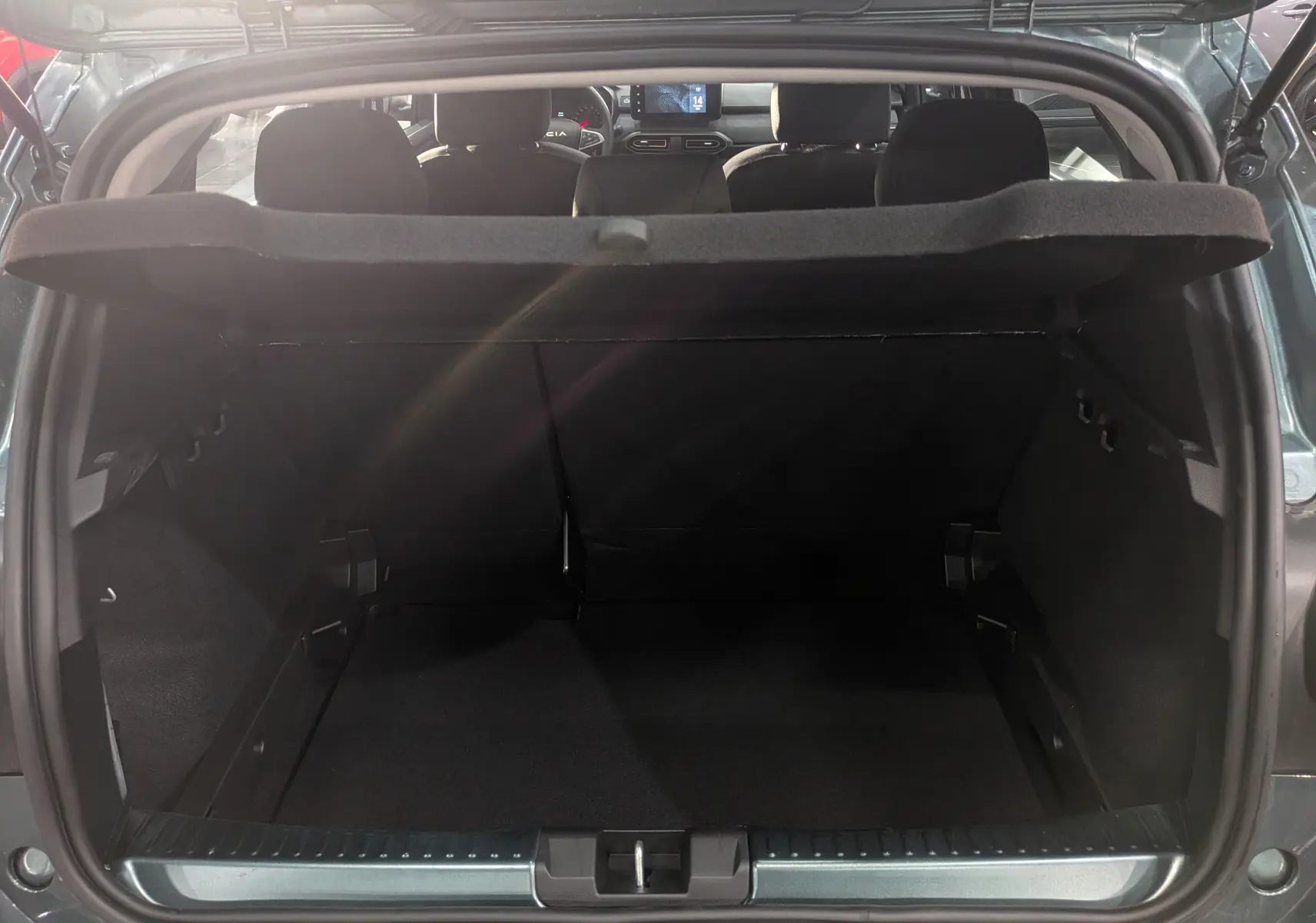 Coffre ouvert d'une Dacia Sandero Stepway TCe 110 Vert Cèdre, vue arrière montrant l'habitacle et la tablette de séparation.