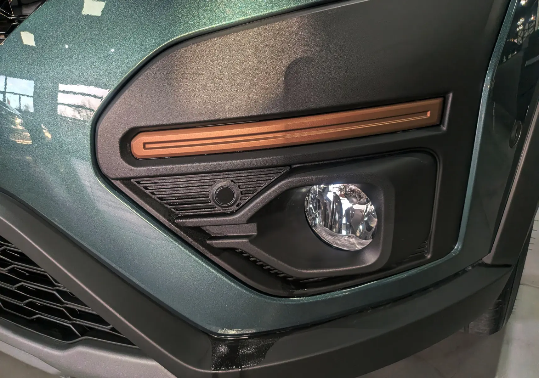 Gros plan sur le feu antibrouillard avant droit du Dacia Sandero Stepway TCe 110 Vert Cèdre 2025.