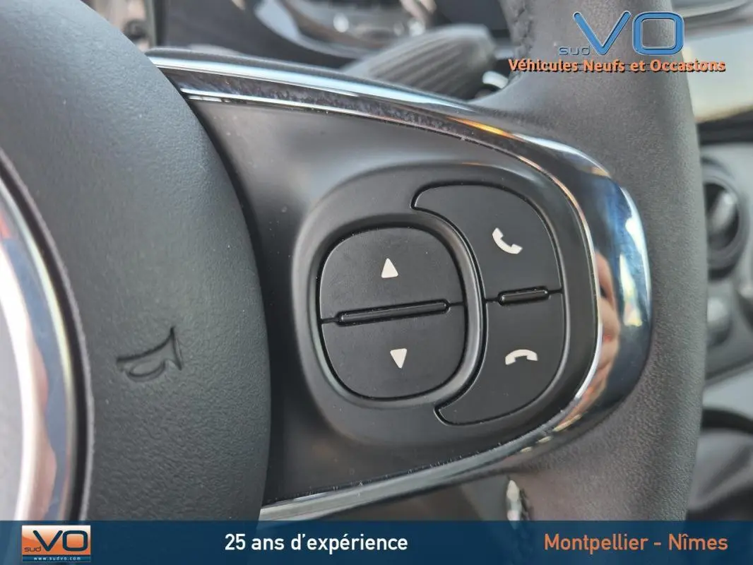 Gros plan sur les commandes de téléphone et volume au volant d'une FIAT 500C noire 2024 hybride essence.