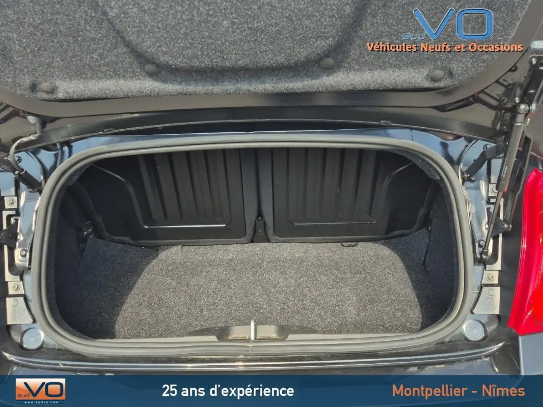 Coffre ouvert vu de dessus d’une FIAT 500C noire 2024 avec roue de secours, montrant l’espace de rangement vide.