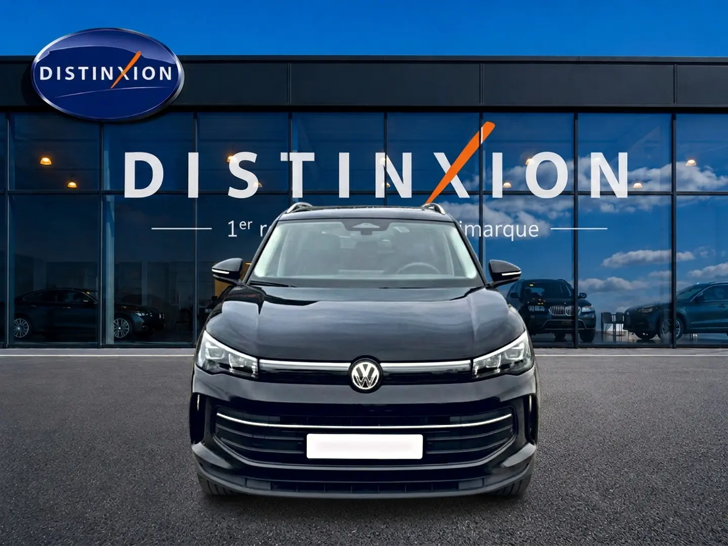 Vue avant d'un Volkswagen Tiguan noir 2025 garé devant une vitrine avec logo Distinxion.