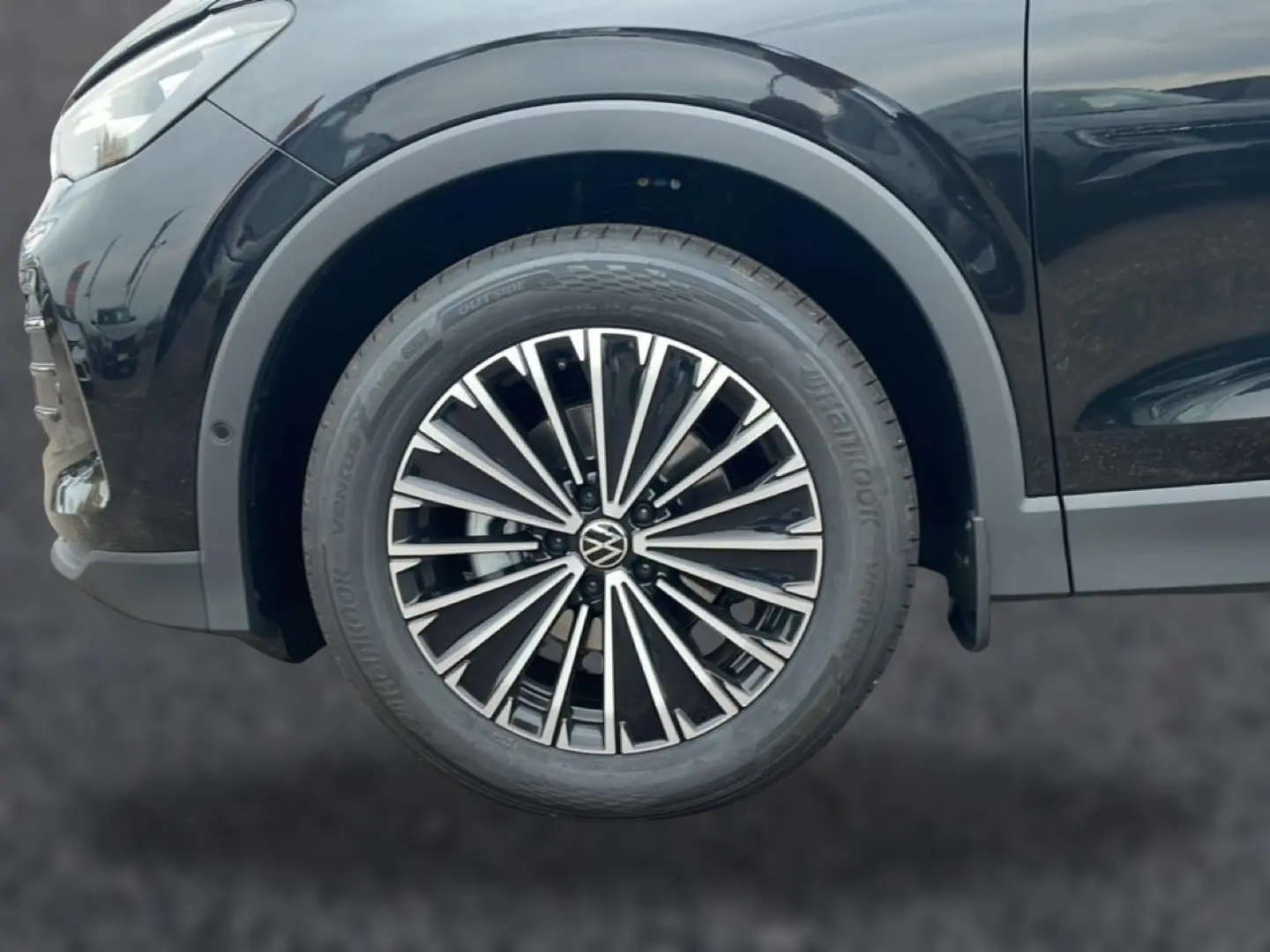 Gros plan sur la roue avant droite du Volkswagen Tiguan noir 2025 avec jante alliage multibranches distinctive.
